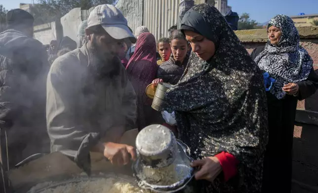 Palestinians collect donated food at a food distribution center in Deir al-Balah, central Gaza Strip, Thursday Jan. 2, 2025. (AP Photo/Abdel Kareem Hana)