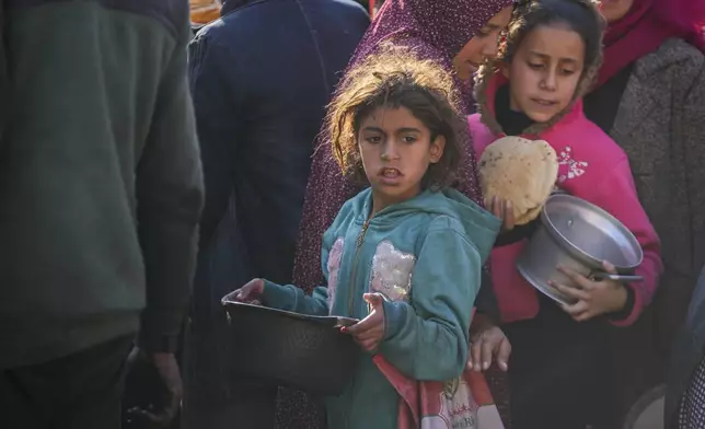 Palestinian girls collect donated food at a food distribution center in Deir al-Balah, central Gaza Strip, Thursday Jan. 2, 2025. (AP Photo/Abdel Kareem Hana)