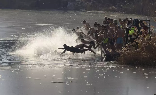 Believers jump in the icy lake to retrieve a wooden cross thrown by Bulgarian Patriarch Danail, in Sofia, Monday, Jan. 6, 2025. (AP Photo/Valentina Petrova)