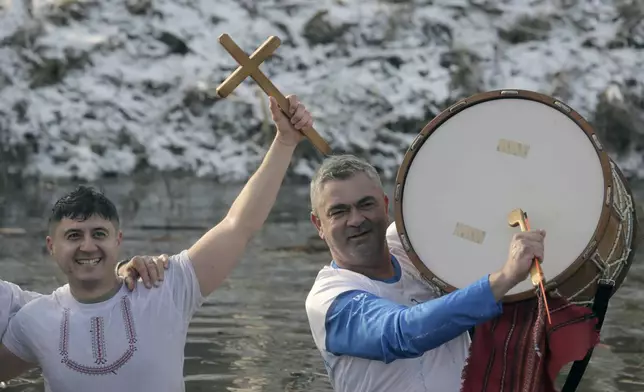 Bulgariana sing and dance and hold a wooden cross in the Lesnovska River during Epiphany Day celebrations in the town of Elin Pelin, Bulgaria, Monday, Jan. 6, 2025. (AP Photo/Valentina Petrova)