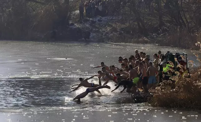 Bulgarian Patriarch Danail throws a wooden cross in the icy lake as believers jump to retrieve it, in Sofia, Monday, Jan. 6, 2025. (AP Photo/Valentina Petrova)