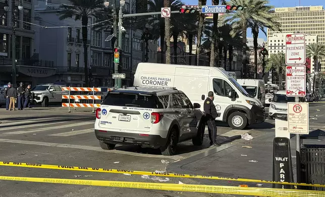 A coroner's van is parked on the corner of Bourbon St. and Canal St, after a vehicle raced into a crowd of revelers early on New Year's Day, in New Orleans on Wednesday, Jan. 1, 2025. (AP Photo/Jack Brook)