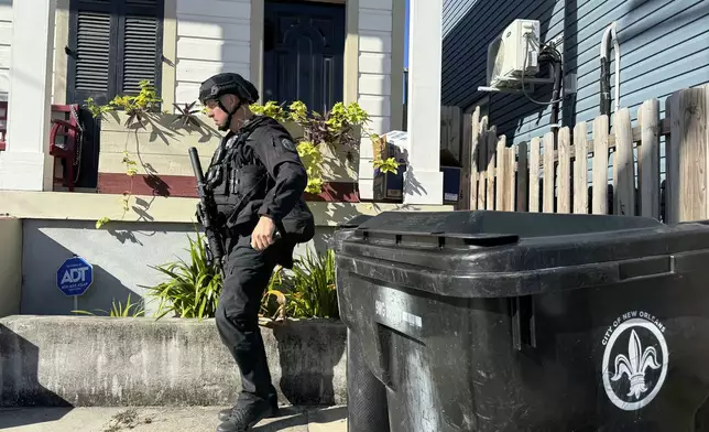 A New Orleans police officer searches the area near a crime scene after a vehicle drove into a crowd on Canal and Bourbon Street earlier, Wednesday Jan. 1, 2025. (AP Photo/Jack Brook)