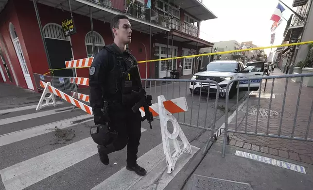 A member of the emergency services walks past a police barricade after a vehicle drove into a crowd on New Orleans' Canal and Bourbon Street, Wednesday Jan. 1, 2025. (AP Photo/Gerald Herbert)