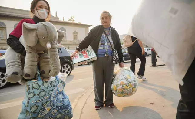 FILE - Actress Gloria Sandoval, middle, is assisted by volunteers after she lost her home in Altadena, Calif., as she leaves a temporary shelter at the Pasadena Convention Center in Pasadena, Calif., Thursday, Jan. 9, 2025. (AP Photo/Damian Dovarganes, File)