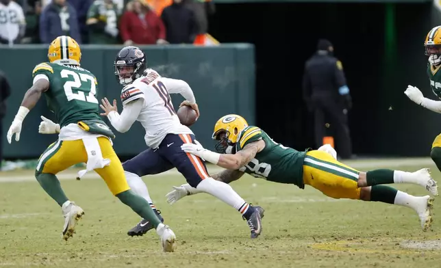 Chicago Bears quarterback Caleb Williams, middle, scrambles against Green Bay Packers linebacker Isaiah McDuffie, bottom, and safety Kitan Oladapo (27) during the second half of an NFL football game, Sunday, Jan. 5, 2025, in Green Bay, Wis. (AP Photo/Mike Roemer)