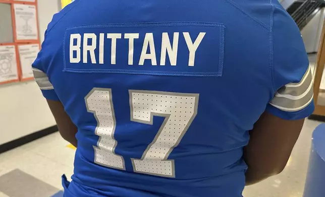 Brittany Sayles, assistant principal at Ann Arbor STEAM, displays the back of the personalized NFL football Detroit Lions jersey she wore to school Thursday, Jan. 16, 2025, in Ann Arbor, Mich. (AP Photo/Mike Householder)