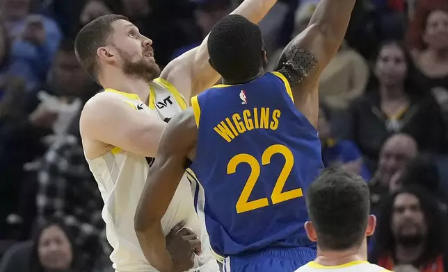 Utah Jazz guard Svi Mykhailiuk, left, shoots against Golden State Warriors forward Andrew Wiggins (22) during the first half of an NBA basketball game in San Francisco, Tuesday, Jan. 28, 2025. (AP Photo/Jeff Chiu)