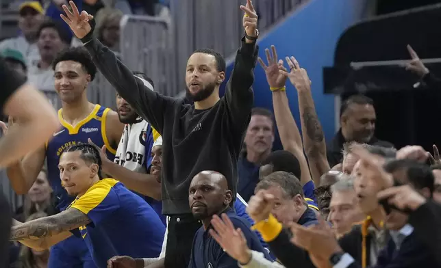 Golden State Warriors guard Stephen Curry, middle, and teammates celebrate on the bench during the first half of an NBA basketball game against the Utah Jazz in San Francisco, Tuesday, Jan. 28, 2025. (AP Photo/Jeff Chiu)