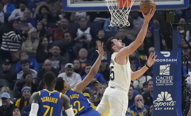 Utah Jazz forward Drew Eubanks, top, shoots against Golden State Warriors guard Dennis Schroder (71) and forward Trayce Jackson-Davis (32) during the first half of an NBA basketball game in San Francisco, Tuesday, Jan. 28, 2025. (AP Photo/Jeff Chiu)
