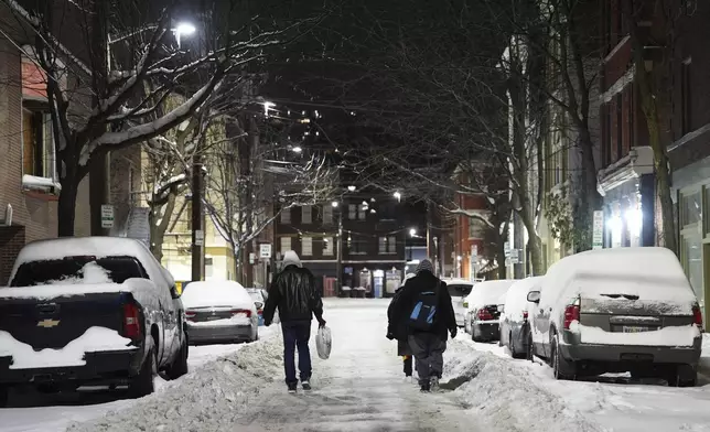 Unhoused people walk down a street toward a shelter after waking up, Tuesday, Jan. 7, 2025, in Cincinnati. (AP Photo/Joshua A. Bickel)