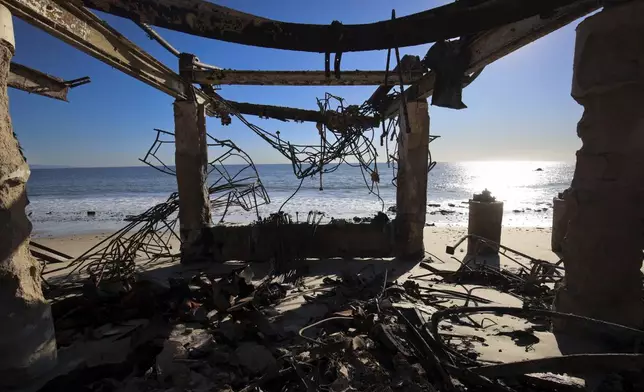 The Pacific Ocean is seen through a fire-ravaged property in the aftermath of the Palisades Fire Tuesday, Jan. 14, 2025 in Malibu, Calif. (AP Photo/Ethan Swope)