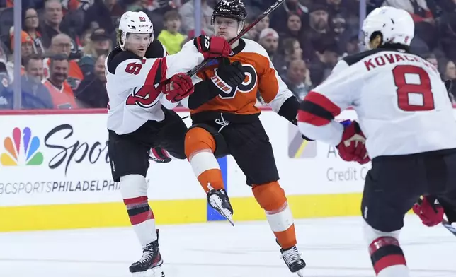 New Jersey Devils' Dawson Mercer, left, and Philadelphia Flyers' Owen Tippett, center, collide during the second period of an NHL hockey game, Monday, Jan. 27, 2025, in Philadelphia. (AP Photo/Matt Slocum)