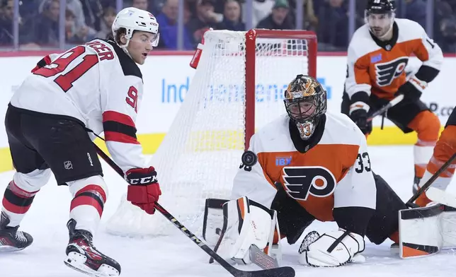 Philadelphia Flyers' Samuel Ersson (33) blocks a shot by New Jersey Devils' Dawson Mercer (91) during the first period of an NHL hockey game, Monday, Jan. 27, 2025, in Philadelphia. (AP Photo/Matt Slocum)