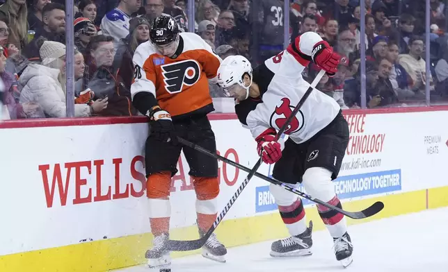 Philadelphia Flyers' Anthony Richard, left, and New Jersey Devils' Johnathan Kovacevic battle for the puck during the second period of an NHL hockey game, Monday, Jan. 27, 2025, in Philadelphia. (AP Photo/Matt Slocum)