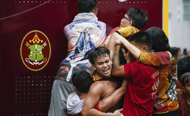 Devotees try to touch the image of Jesus Nazareno inside a glass-covered carriage during its annual procession in Manila, Philippines Thursday, Jan. 9, 2025. (AP Photo/Basilio Sepe)