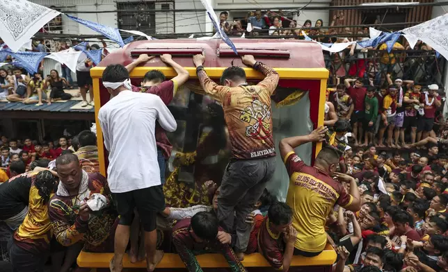 Devotees try to climb on a glass-covered carriage carrying the image of Jesus Nazareno during its annual procession in Manila, Philippines Thursday, Jan. 9, 2025. (AP Photo/Basilio Sepe)