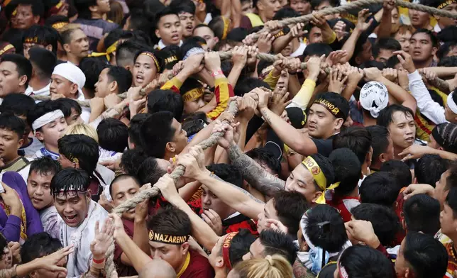 Devotees grab the rope as they pull a glass-covered carriage carrying the image of Jesus Nazareno during its annual procession in Manila, Philippines Thursday, Jan. 9, 2025. (AP Photo/Basilio Sepe)