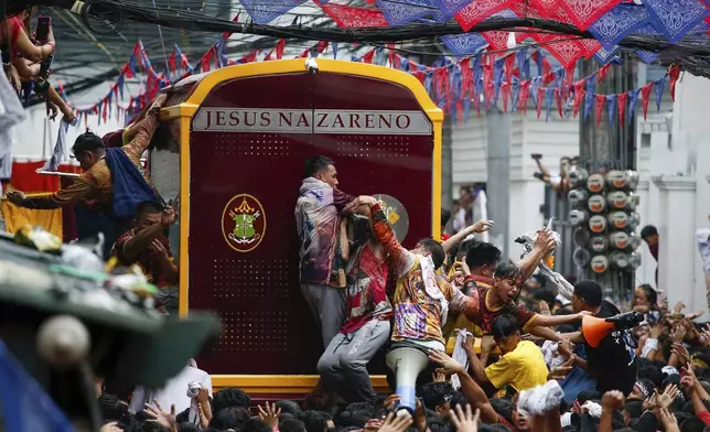 Devotees try to climb on a glass-covered carriage carrying the image of Jesus Nazareno during its annual procession in Manila, Philippines Thursday, Jan. 9, 2025. (AP Photo/Basilio Sepe)