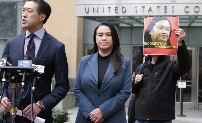 Former Oakland Mayor Sheng Thao stands next to her lawyer Jeff Tsai outside the United States District Court after a hearing in Oakland, Calif., Friday, Jan. 17, 2025, as Tuan Ngo, founder of Asians Unite, protests at right. (Santiago Mejia/San Francisco Chronicle via AP)