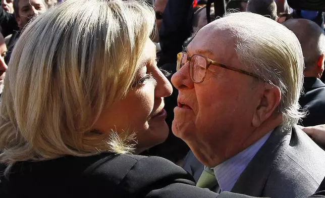 FILE - French far-right politician Jean Marie Le Pen, right kisses his daughter, France's far-right National Front candidate for the presidential election Marine Le Pen prior to a wreath-laying ceremony at the statue of Joan of Arc, during the traditional May Day march in Paris, Tuesday May 1, 2012. (AP Photo/Francois Mori, File)