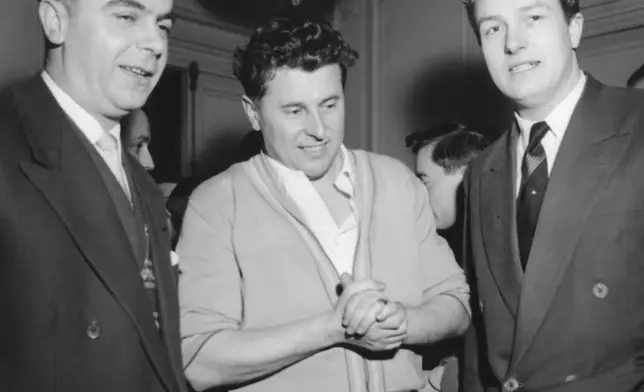 FILE - Pierre Poujade, center, whose newly formed anti-tax party has surprised the world by winning at least 50 seats in the French elections, with Andre Gayard, left, and Jean-Marie Le Pen, right, chats with two members of this party who have been elected to parliament, at his headquarters in Ablon, near Paris, France on Jan. 3, 1956. (AP Photo/H. Babout, File)