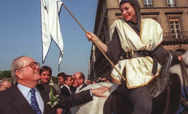 FILE - National Front party leader Jean-Marie Le Pen, left, pats a horse ridden by Francoise, posing as Joan of Arc, Thursday May 1, 1997 during a party rally. (AP Photo/Michel Lipchitz, File)