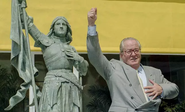 FILE - National Front leader Jean Marie Le Pen mimics Joan of Arc brandishing the French flag before a press conference held Wednesday June 21, 1995 in St Cloud, west of Paris. (AP Photo/Remy de la Mauviniere, File)