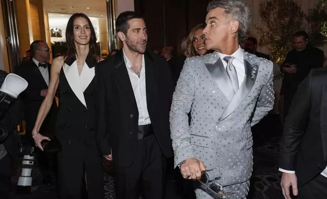 Jeanne Cadieu, from left, Jake Gyllenhaal, and Robbie Williams arrive at the 82nd Golden Globes on Sunday, Jan. 5, 2025, at the Beverly Hilton in Beverly Hills, Calif. (AP Photo/Chris Pizzello)