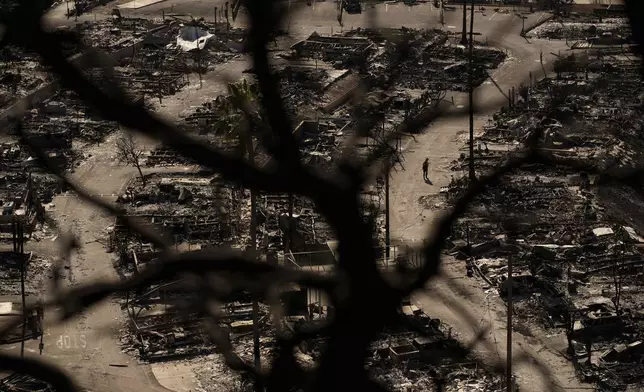 A firefighter walks along a road in a fire-ravaged community in the aftermath of the Palisades Fire in the Pacific Palisades neighborhood of Los Angeles, Monday, Jan. 13, 2025. (AP Photo/John Locher)