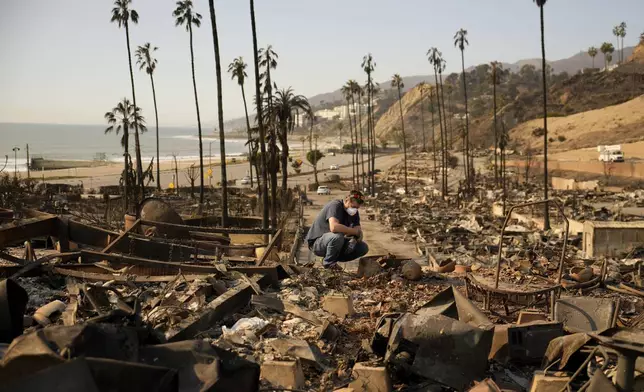 Kevin Marshall sifts through his mother's fire-ravaged property in the the Palisades Fire in the Pacific Palisades neighborhood of Los Angeles, Saturday, Jan. 11, 2025. (AP Photo/John Locher)