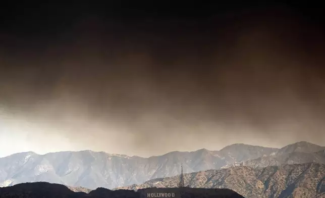 Thick heavy smoke from wildfires passes over the Hollywood sign in Los Angeles on Wednesday, Jan. 8, 2025. (AP Photo/Richard Vogel)