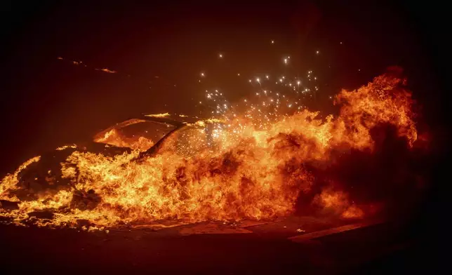 A vehicle burns as the Palisades Fire advances in the Pacific Palisades neighborhood of Los Angeles, Tuesday, Jan. 7, 2025. (AP Photo/Ethan Swope)