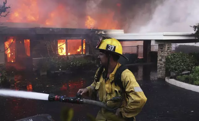 CORRECTS BYLINE FROM ETIENNE LAURENT TO ETHAN SWOPE - A firefighter battles the Palisades Fire as it burns a residence in the Pacific Palisades neighborhood of Los Angeles, Tuesday, Jan. 7, 2025. (AP Photo/Ethan Swope)