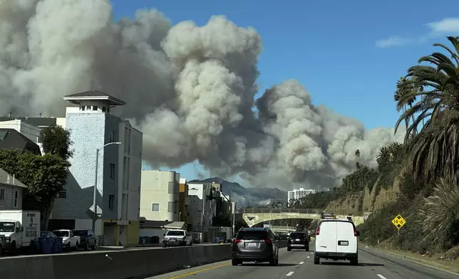 Heavy smoke from a brush fire in the Pacific Palisades rises over the Pacific Coast Highway in Santa Monica, Calif., on Tuesday, Jan. 7, 2025. (AP Photo/Eugene Garcia)