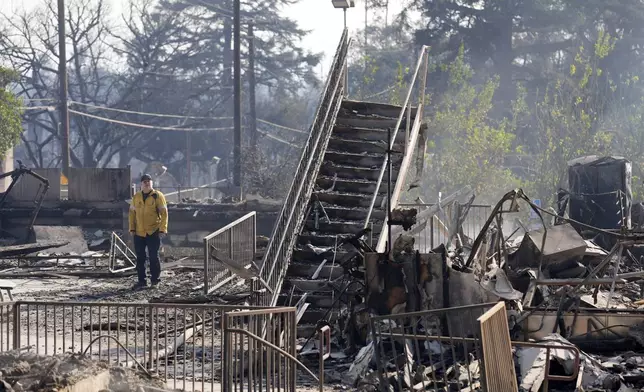 A firefighter studies the charred remains of St. Mark's School, a preschool and K-6 grade school on Altadena Drive, Friday, Jan. 10, 2025, in Altadena, Calif. (AP Photo/Chris Pizzello)