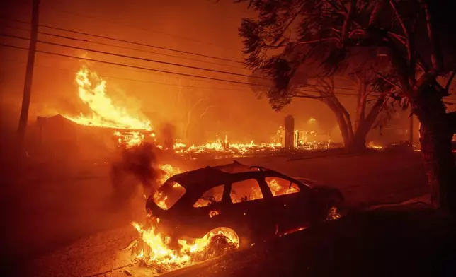 The Palisades Fire burns vehicles and structures in the Pacific Palisades neighborhood of Los Angeles, Tuesday, Jan. 7, 2025. (AP Photo/Ethan Swope)