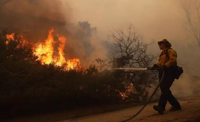 A firefighter battles the advancing Palisades Fire in the Pacific Palisades neighborhood of Los Angeles, Tuesday, Jan. 7, 2025. (AP Photo/Etienne Laurent)