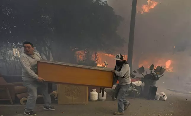 Residents along Braeburn Road rush to save property as a home burns behind them during the Eaton fire in Altadena Wednesday morning Jan. 8, 2025. (Will Lester/The Orange County Register via AP)