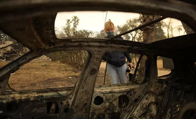 Lisa Renn looks at remains of car in Altadena, Calif., Thursday, Jan. 9, 2025. (AP Photo/John Locher)