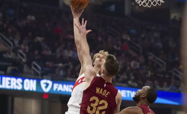 Toronto Raptors' Gradey Dick, left, shoots over Cleveland Cavaliers' Dean Wade (32) as Cavaliers' Evan Mobley, watches, looks on during the first half of an NBA basketball game in Cleveland, Thursday, Jan. 9, 2025. (AP Photo/Phil Long)