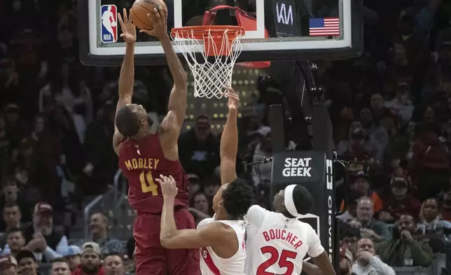 Cleveland Cavaliers' Evan Mobley (4) shoots in front of Toronto Raptors' Scottie Barnes, center, and Chris Boucher (25) during the first half of an NBA basketball game in Cleveland, Thursday, Jan. 9, 2025. (AP Photo/Phil Long)