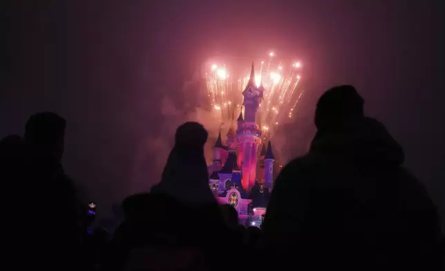 A light show is projected on the castle of Sleeping Beauty as fireworks explode in Disneyland, in Marne-la-Vallee, east of Paris, Friday Jan. 17, 2025. (AP Photo/Thibault Camus)
