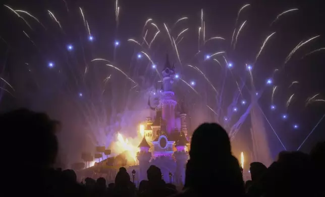 A light show is projected on the castle of Sleeping Beauty as fireworks explode in Disneyland, in Marne-la-Vallee, east of Paris, Friday Jan. 17, 2025. (AP Photo/Thibault Camus)