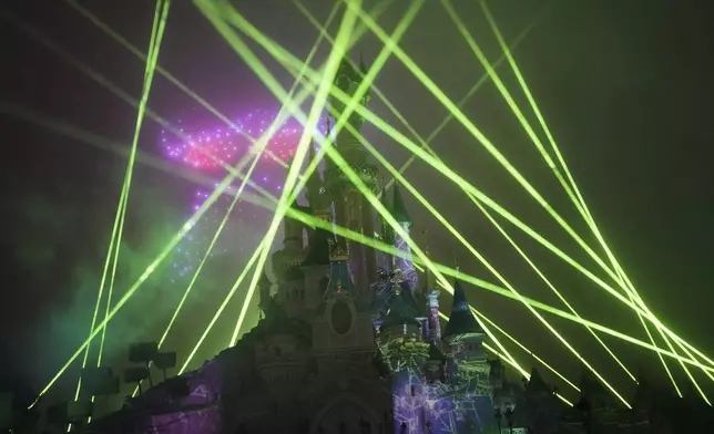 A light show is projected on the castle of Sleeping Beauty as fireworks explode in Disneyland, in Marne-la-Vallee, east of Paris, Friday Jan. 17, 2025. (AP Photo/Thibault Camus)