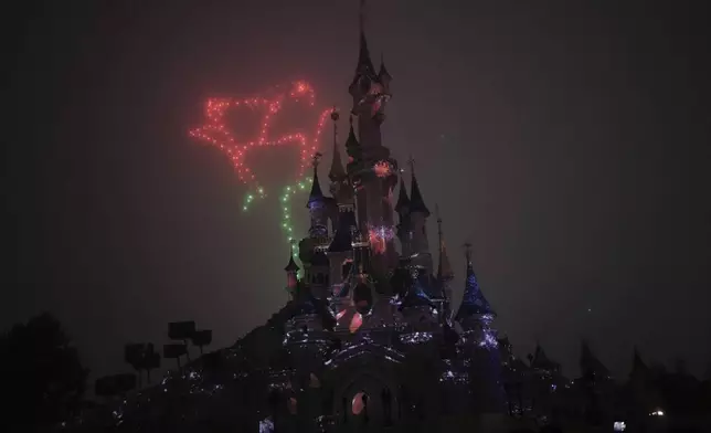 A light show is projected on the castle of Sleeping Beauty as fireworks explode in Disneyland, in Marne-la-Vallee, east of Paris, Friday Jan. 17, 2025. (AP Photo/Thibault Camus)