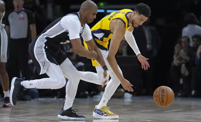 Indiana Pacers guard Tyrese Haliburton (0) and San Antonio Spurs guard Chris Paul (3) go for a loose ball during the first half of a Paris Games 2025 NBA basketball game in Paris, Saturday, Jan. 25, 2025. (AP Photo/Thibault Camus)
