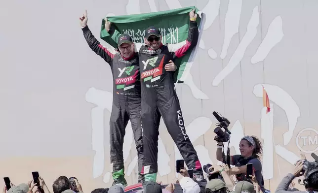 Driver Yazeed Al Rajhi, of Saudi Arabia, right, and co-driver Timo Gottschalk, of Germany celebrate winning the Dakar Rally after the twelfth stage in Shubaytah, Saudi Arabia, Friday, Jan. 17, 2025. (AP Photo/Christophe Ena)
