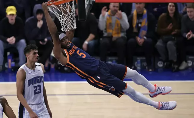 New York Knicks forward Precious Achiuwa (5) hangs from the rim after slam-dunking in front of Orlando Magic forward Tristan da Silva (23) during the first half of an NBA basketball game Monday, Jan. 6, 2025, in New York. (AP Photo/Adam Hunger)