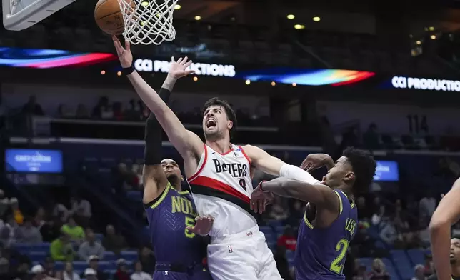 Portland Trail Blazers forward Deni Avdija (8) goes to the basket between New Orleans Pelicans guard Dejounte Murray (5) and center Yves Missi in the first half of an NBA basketball game in New Orleans, Wednesday, Jan. 8, 2025. (AP Photo/Gerald Herbert)